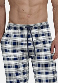 Plaid shorts featuring a navy and white pattern, elastic waistband with drawstring, and lightweight fabric. Suitable for leisure or sleepwear.