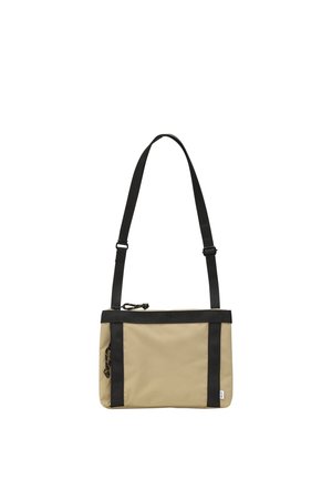 Beżowa prostokątna torba na ramię z czarnym regulowanym paskiem i wykończeniem, z główną komorą na zamek oraz detalem bocznego suwaka.