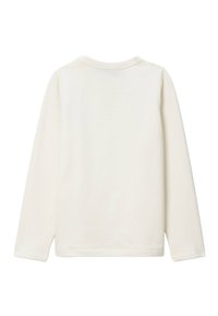 Chemise à manches longues de couleur écrue, en coton doux, avec un col rond et des lignes simples et épurées sans motifs visibles.