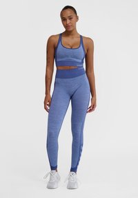 Blå sportbehå och leggings set i ett strukturerat, stretchigt tyg. Behån har smala axelband, medan tightsen har en hög midja och mesh-accenter.