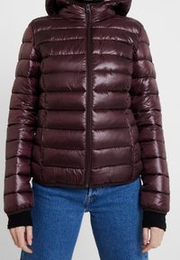 Burgundy padded jacket with a glossy finish, featuring a zip closure, hood, and ribbed cuffs. Quilted design with horizontal rows.