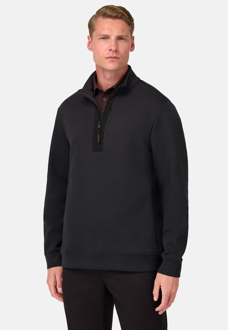 Čierny pulóver s polovičným zipsom vyrobený z mäkkej tkaniny, s vysokým golierom, dlhými rukávmi a bočnými panelmi. Čisté línie a minimalistický dizajn.