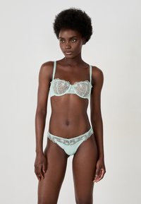 Mintgrünes Dessous-Set mit einem Balconette-BH mit floralen Spitze-Details und passenden Slips, die beide aufwendige Stickereien zeigen.