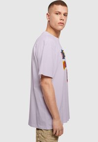 Lavendel bomulds t-shirt med en afslappet pasform, som har farverig grafisk tekst trykt på fronten. Korte ærmer og rund halsudskæring.