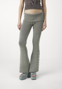 Grå stickade utsvängda byxor med breda muddar. Har vertikal ribbad textur och dekorativa knappar på sidan. Kombineras med plattformsko.