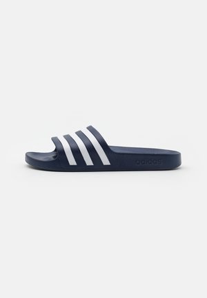 Marineblauwe slipper met drie witte strepen over de bovenkant. Gemaakt van gestructureerd synthetisch materiaal, met een platte zool en een gebogen voetbed.