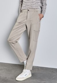Beiga cargo-byxor med rak passform, med framfickor och knäppning. Tillverkade av slätt tyg, i en avslappnad design.