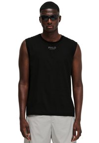 Svart ärmlös tröja med rund hals och subtil logotyp. Bärs med mörka solglasögon. Slät tyg; minimalistisk design.