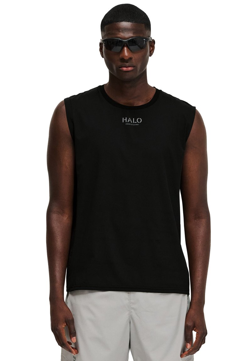 Svart ärmlös tröja med rund hals och subtil logotyp. Bärs med mörka solglasögon. Slät tyg; minimalistisk design.