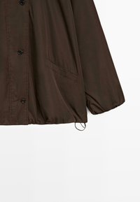 Veste marron à boutons avec poignets élastiques, poches avant inclinées et cordon de serrage réglable à l'ourlet.