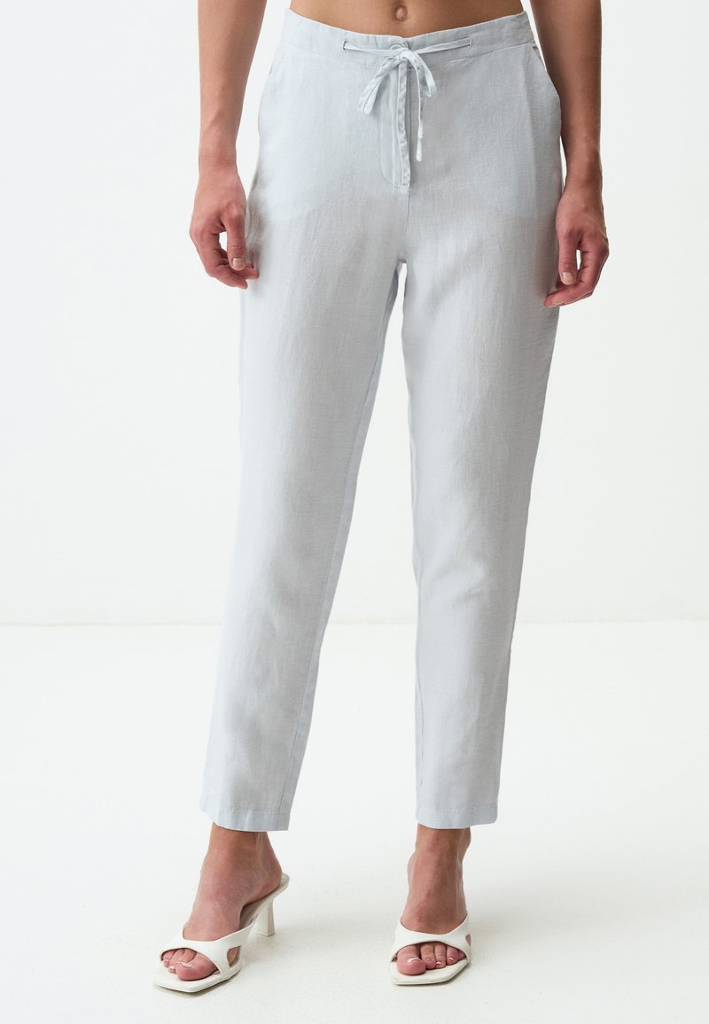 Lichtgrijze linnen broek met een koord in de taille, slim fit, taps toelopende benen en twee zijzakken, gecombineerd met witte open teenhakken.