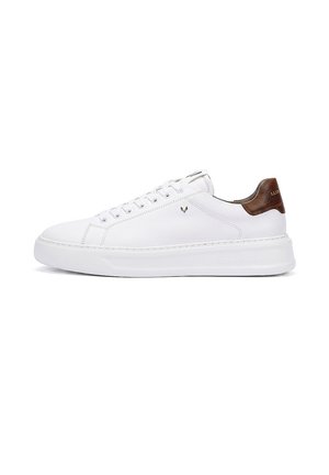 Zapatilla blanca de caña baja con cordones en la parte delantera, suela gruesa y lengüeta de cuero marrón en el talón sobre un fondo blanco.