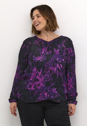 Blouse noire à manches longues avec un motif floral violet, décolleté en V, coupe relaxée, texture douce et poignets boutonnés.