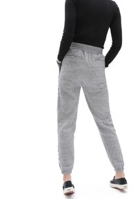 Graue Jogginghose mit strukturiertem Finish, elastischem Bund, seitlichen Taschen und eng anliegenden Bündchen. Kombiniert mit schwarzen Slippers.