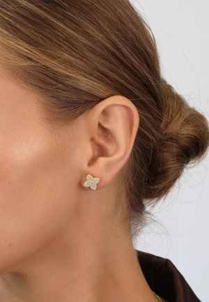 Goldene, schmetterlingsförmige Ohrringe, verziert mit klaren Edelsteinen, mit sichtbarem Stecker-Verschluss, die aufwendige Details und eine strukturierte Oberfläche präsentieren.