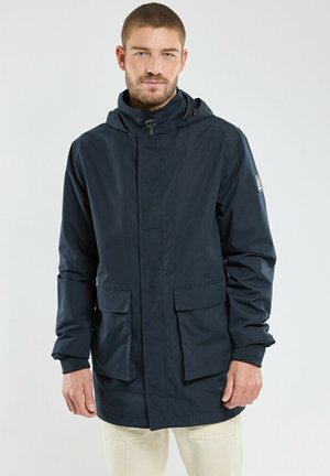 Veste imperméable bleu marine avec capuche, manches longues et deux poches avant à rabat. Texture lisse et détails de design minimalistes.