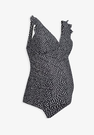 Fekete, egyrészes kismama fürdőruha, fehér pöttyökkel, fodros vállpántokkal és redőzött textúrával a testen.
