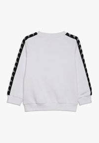 Felpa bianca con strisce laterali nere caratterizzata da un motivo grafico ripetuto. Tessuto morbido, polsini a costine e scollo rotondo.