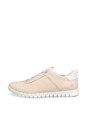 Sneaker beige basso con suola bianca, stringhe sul davanti, collo imbottito e un piccolo logo vicino al tallone su sfondo bianco.