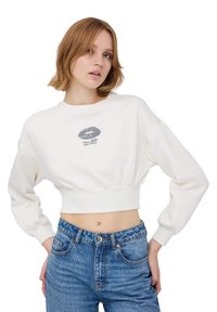 Biały, krótki sweatshirt z okrągłym dekoltem, marszczonym dołem oraz grafiką ust z napisem "Więcej miłości, proszę". Długie rękawy.