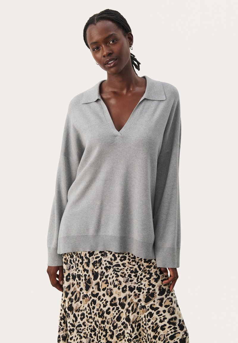 Grå strikket sweater med V-hals og krave, med en afslappet pasform og lange ærmer, lagd over en leopardmønstret maxinederdel.