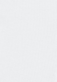 Biała, prążkowana tkanina ukazująca miękką, teksturowaną powierzchnię z pionowymi liniami. Jednolity kolor w całej tkaninie, minimalna zmiana w wzorze.