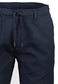 I pantaloni in cotone blu navy presentano una vita elastica con cordoncino, pieghe frontali e terminali metallici sui lacci per un tocco di dettaglio in più.