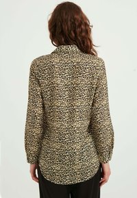 Plejset skjorte i leopardmønster i tan og sort, letvægtsstof, lange ærmer, knappede manchetter og en afslappet pasform med en let buet nederkant.