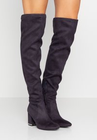 Over-the-knee stövlar i mörklila mocka, med en kraftig klack och sidodragkedja, med en mjuk textur och figurnära design.