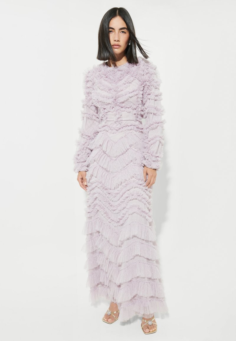 Lavendel maxi-klänning med tierad volangdesign, långärmar och en figurnära liv. Mjukt, texturerat tyg med en flödande siluett.