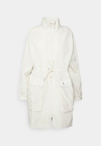 Veste blanche légère avec col montant, fermeture zippée à l'avant et taille ajustable avec cordon de serrage. Comprend deux grandes poches avant et un écusson logo.