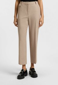 Beige wijde broek met een gestructureerde stof, voorzien van zijzakken en een gepolijst uiterlijk, gecombineerd met zwarte chunky loafers.