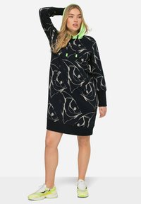 Robe noire à capuche avec des motifs abstraits argentés, dotée d'une capuche et de cordons de serrage verts néon, fabriquée en tissu doux et texturé.