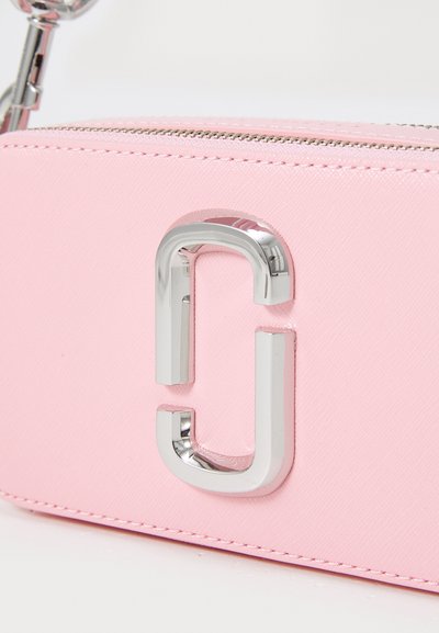Pink synthetic leather bag featuring a silver-tone logo accent and zip closure. Smooth texture with stitched detailing along the edges.