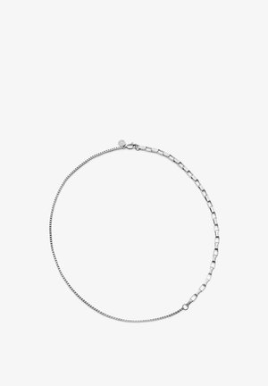 Sølvkjede med to forskjellige lenkestiler forbundet med en lås i krepsemotiv, vist på hvit bakgrunn.