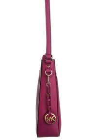 Borsa a tracolla fucsia in pelle con silhouette slanciata, hardware color oro e un charm decorativo con il logo MK attaccato alla tracolla.