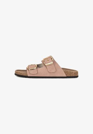 Pink suede slide sandal with two adjustable gold buckles, cork footbed, and textured black sole. Open-toe design and minimalist style.
