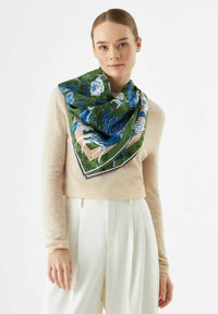 Groene zijden sjaal met een bloempatroon in blauw en wit, met een driehoekige vorm en een contrasterende neutrale rand. Glad van textuur.