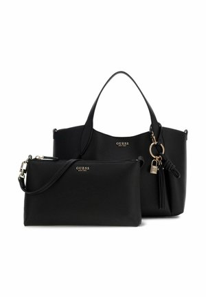 Bolso negro Guess con dos asas y bolso de mano negro a juego con correa para el hombro, ambos con logos dorados y un adorno de borla y cierre decorativo.