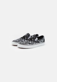 Black slip-on shoes featuring a white bandana pattern with skulls, textured fabric upper, and a white rubber sole.