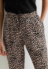 Leopardprint broek in tan en zwart. Voorzien van een elastische tailleband met een trekkoord, zijzakken en een ontspannen pasvorm. Zachte textuur.