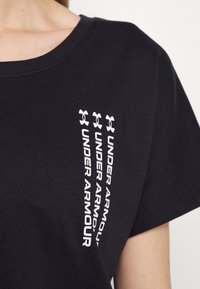 Svart kortärmad t-shirt med rund halsringning, med tre vertikala vita tryck av "UNDER ARMOUR" och logotypen på vänster sida.