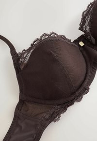 Dark brown lace and mesh bra with underwire and adjustable straps on a light background.