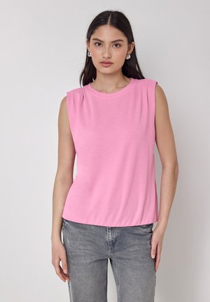 Haut sans manches rose en tissu doux avec un col rond et de subtils plissés aux épaules, associé à un jean en denim gris.