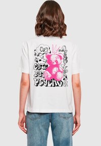 T-shirt en coton blanc avec un graphique d'ours en peluche rose et des croquis colorés. Coupe décontractée avec des manches courtes et un ourlet droit.
