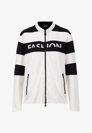 Witte jas met ritssluiting en zwarte horizontale strepen op de mouwen en borst, met het woord "FASHION" in dikke letters op de borstband.