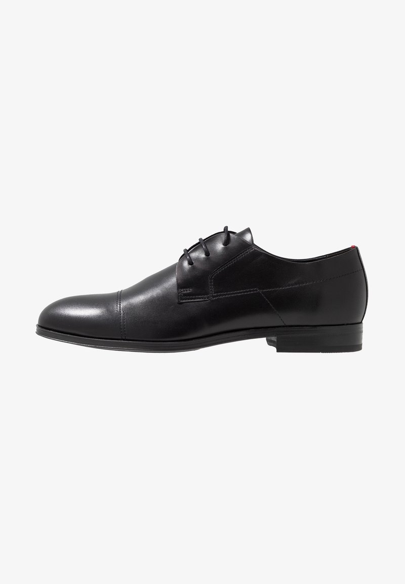 Chaussure habillée pour homme en cuir noir avec bout rapporté, trois œillets pour lacets et talon bas empilé, vue de profil droit sur fond blanc.