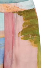 Zbliżenie kolorowych spodni z abstrakcyjnym wzorem pociągnięć pędzla w odcieniach zieleni, różu, niebieskiego i beżu oraz elastycznym pasem.