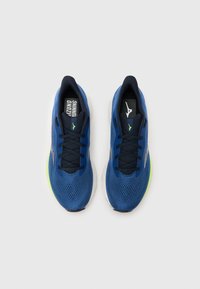 Modré bežecké topánky s priedušným sieťovinovým zvrškom, tmavými šnúrkami, bielymi a zelenými akcentmi a logom na jazyku. Majú elegantný, aerodynamický dizajn.