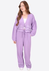 Lavendelfarbenes Zweiteiler-Outfit mit einer verkürzten Strickjacke mit gewelltem Saum und passenden Hosen mit bestickten Akzenten. Strukturierter Stoff.
